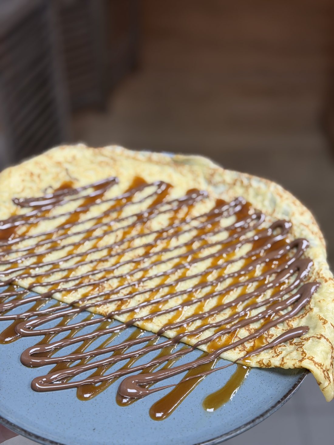 Crêpe de froment nappée de caramel au beurre salé et de Nutella, servie sur une assiette bleue