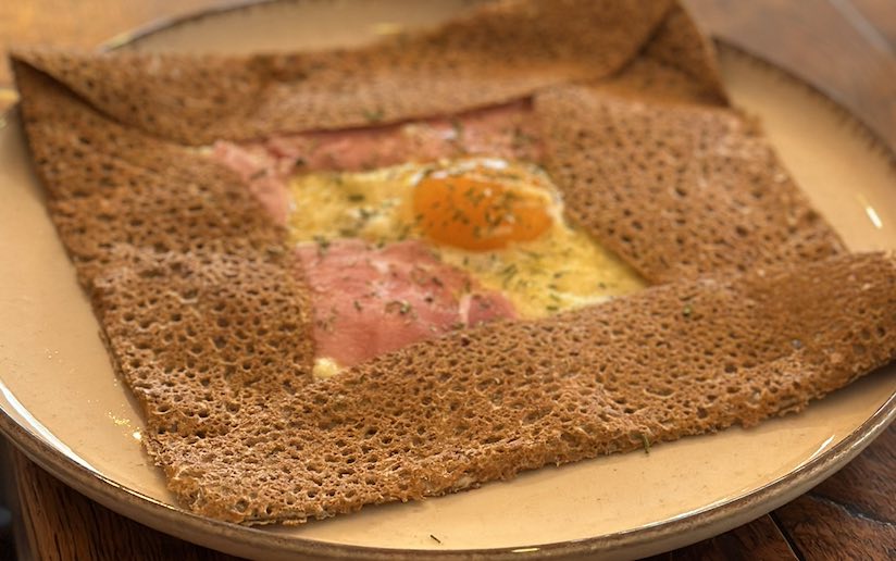 Gros plan sur les bords dentelés et croustillants d'une galette de sarrasin garnie d'œuf et de jambon